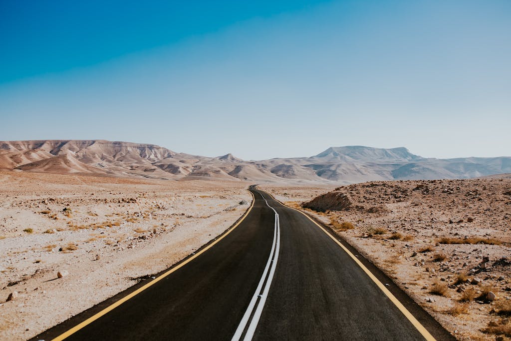Captivating view of an empty road through the arid Negev desert landscape under a clear sky.