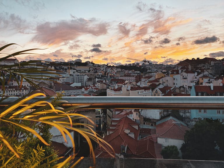 Vibrant cityscape of Lisbon at sunset with picturesque rooftops and colorful sky.
