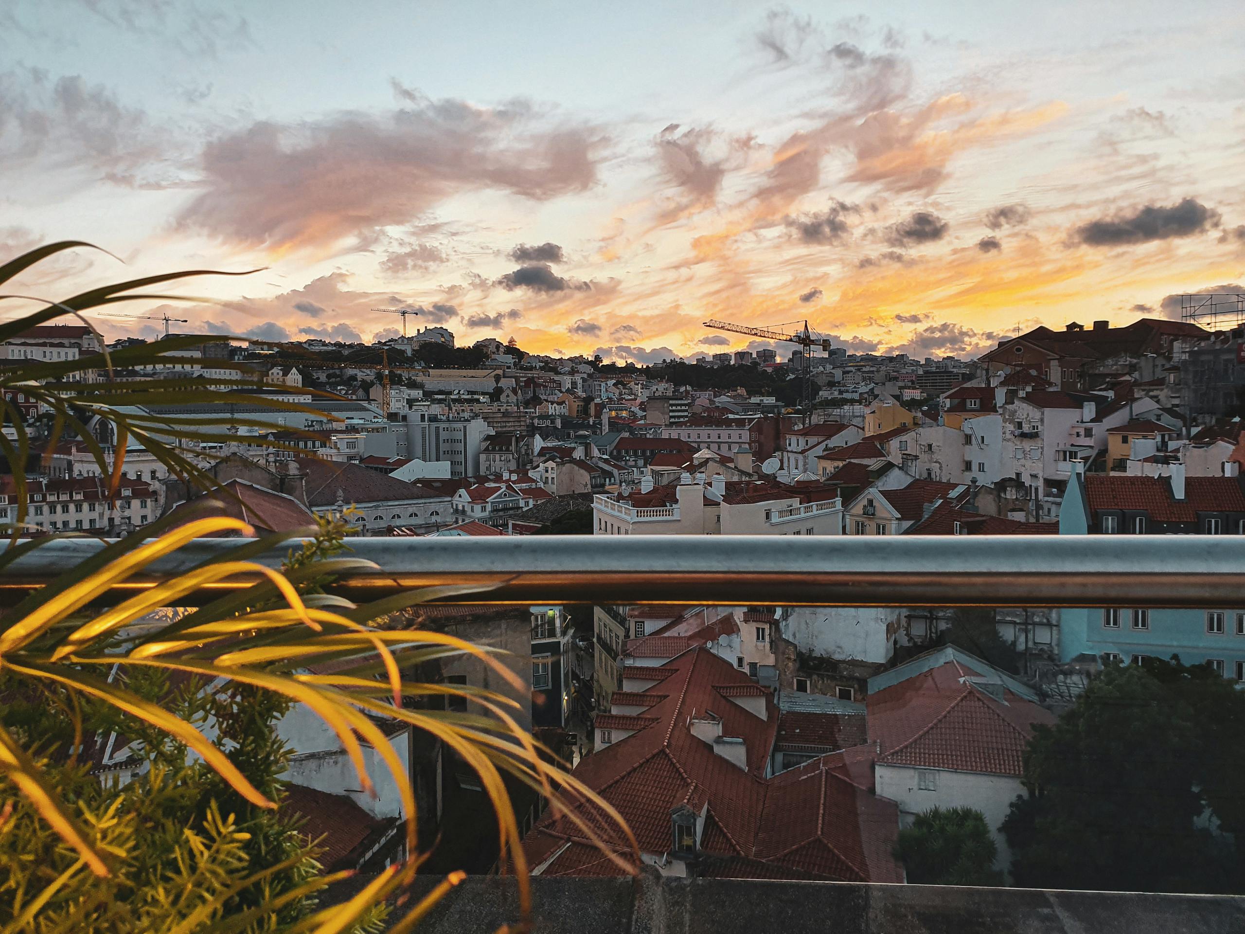 Vibrant cityscape of Lisbon at sunset with picturesque rooftops and colorful sky.